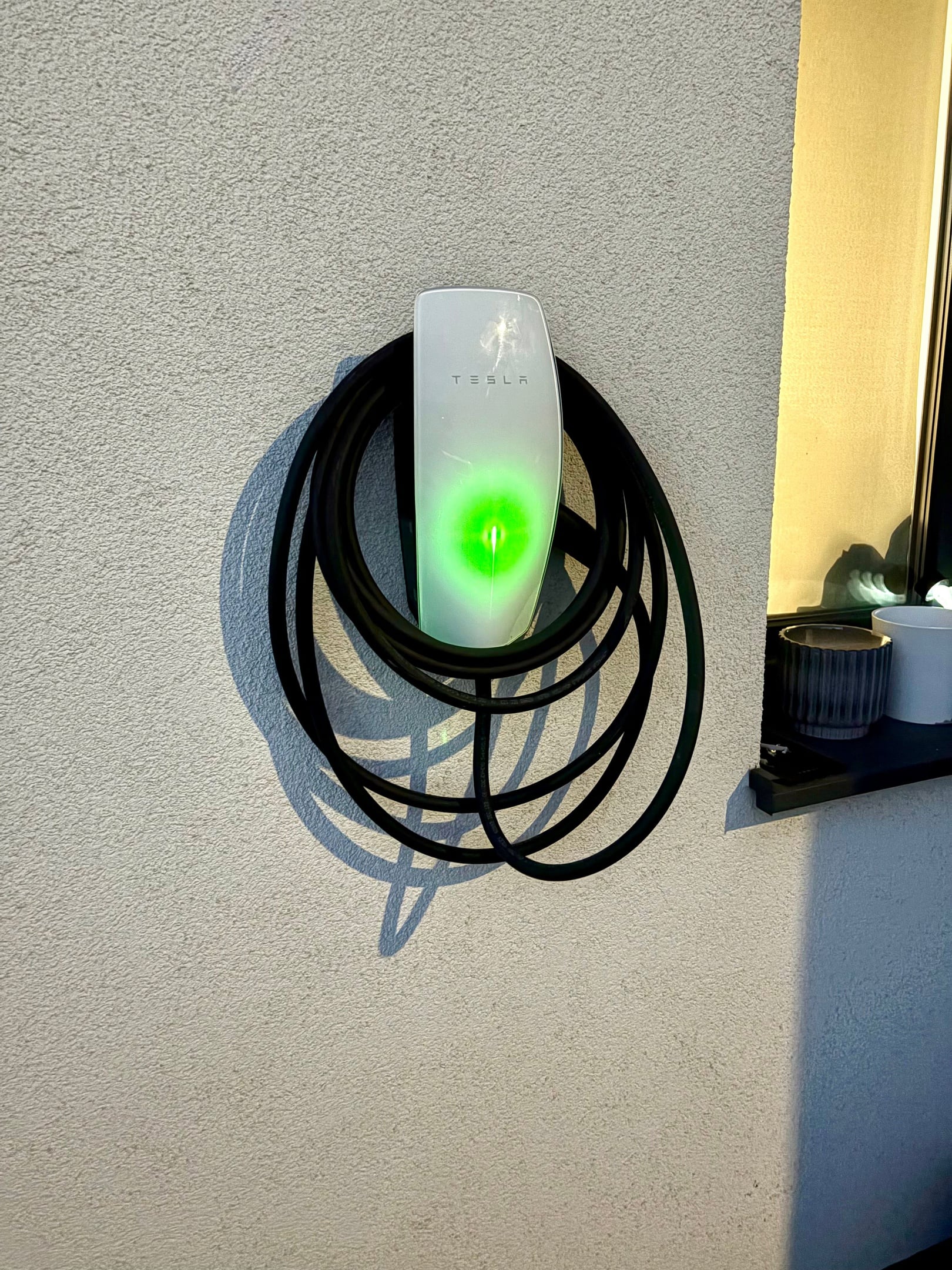Tesla Wall Connector s navinutým nabíjacím káblom na fasáde rodinného domu v Miloslavove